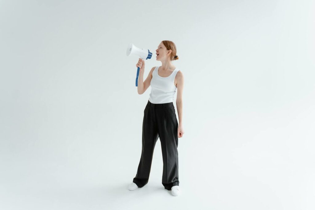 A Woman in White Tank Top and Black Pants Holding a Megaphone